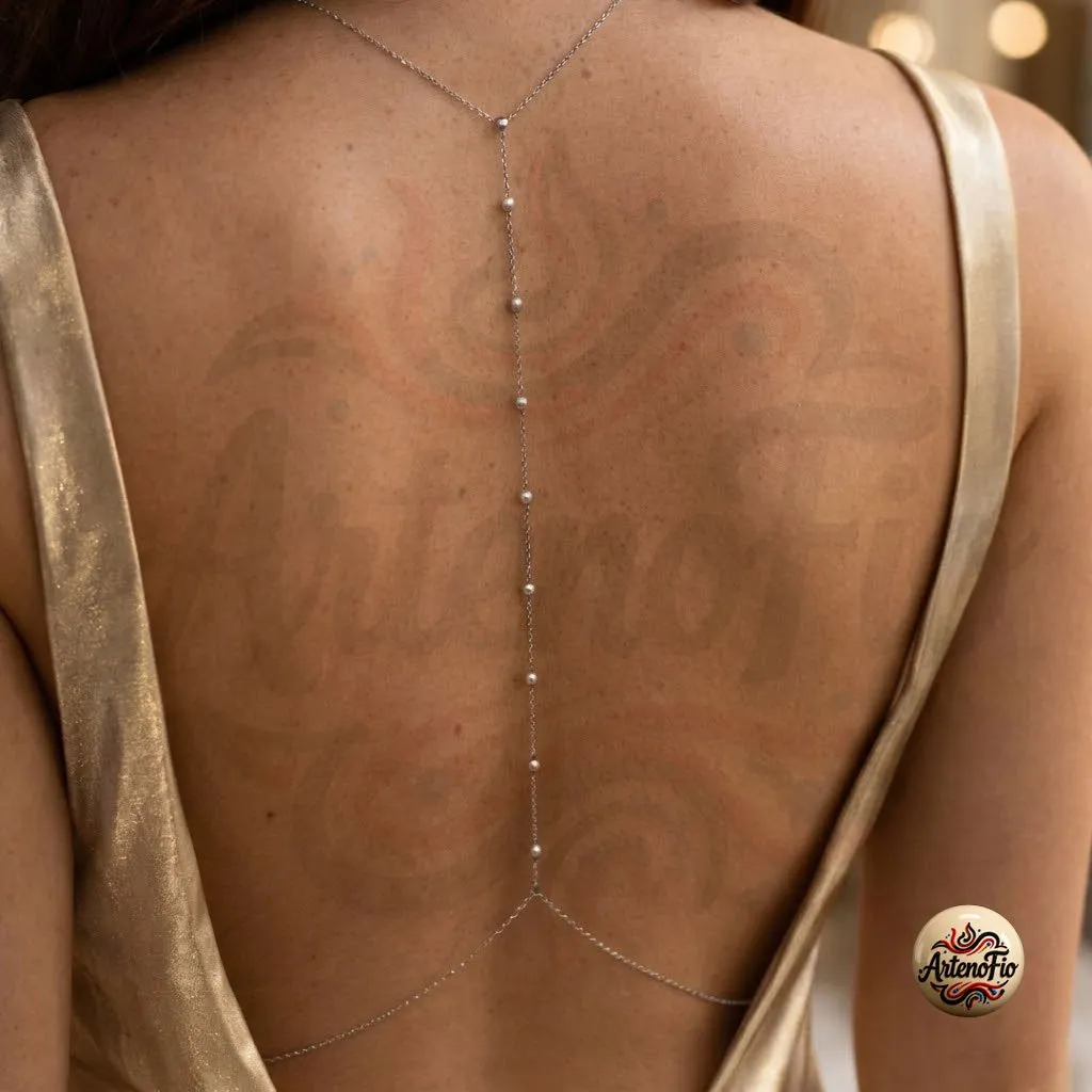 Mulher usando biquíni branco na água com a joia corporal body chain em aço inox cruzando o colo e a cintura, destacando o brilho prateado da peça