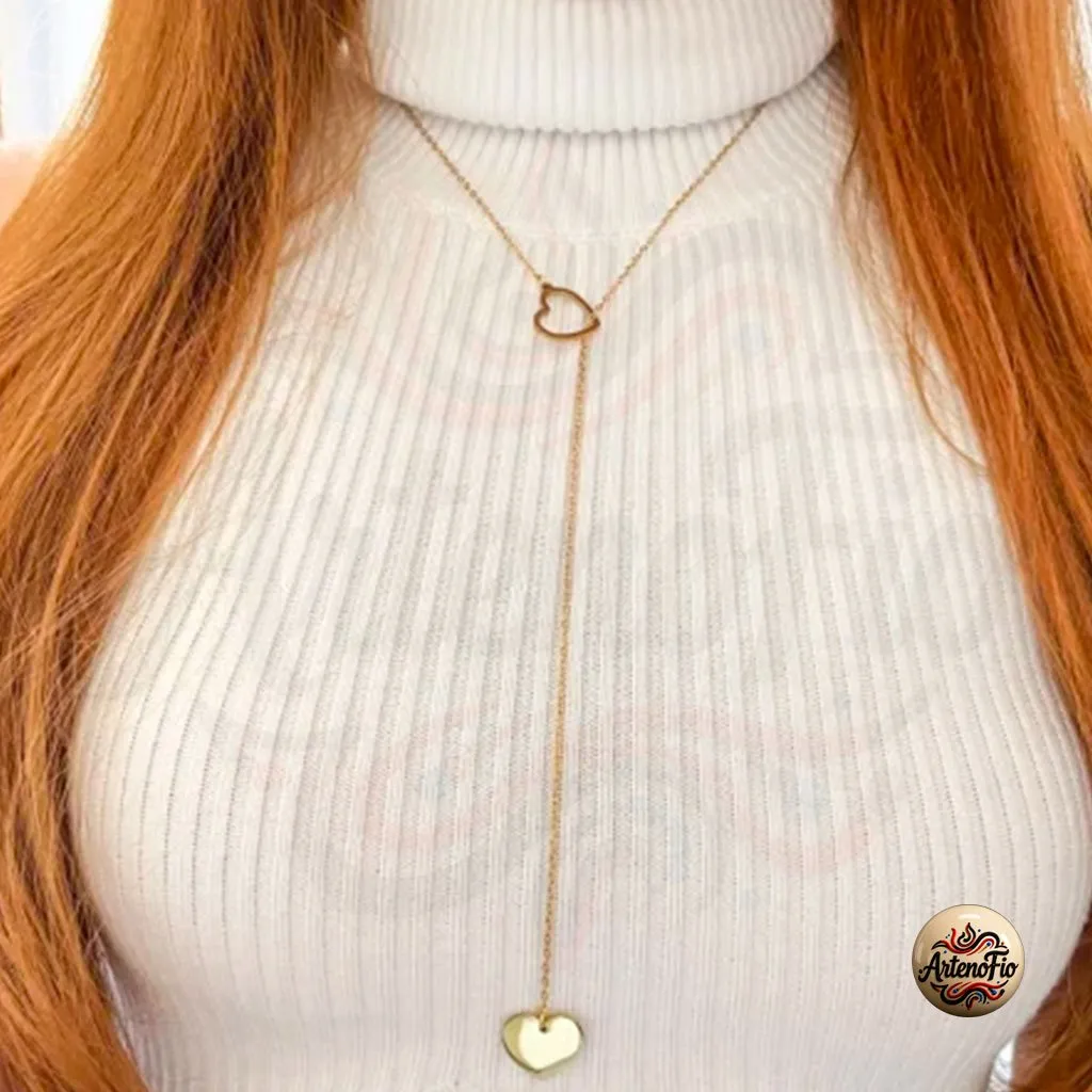 Imagem de pessoa vestindo blusa branca e usando colar gravatinha de aco inox com pingentes de coracao dourados.