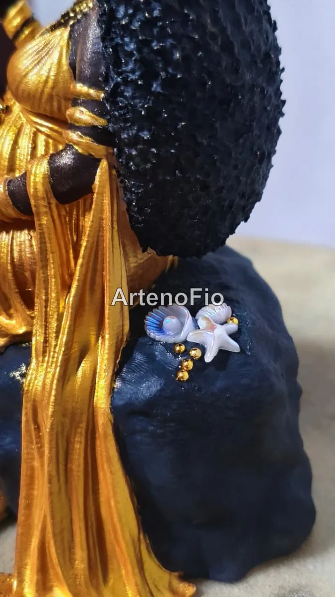 Imagem da orixá Oxum grávida, feita em 3D e pintada à mão em tons dourados, sentada em uma rocha. 2
