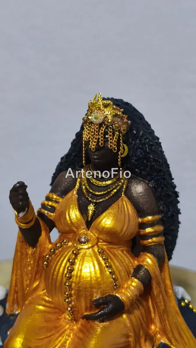 Imagem da orixá Oxum grávida, feita em 3D e pintada à mão em tons dourados, sentada em uma rocha. 3